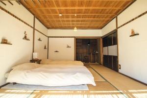 a bedroom with a bed and a wooden ceiling at Hostel Yui-an in Nagiso