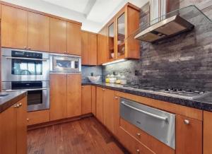 Una cocina con gabinetes de madera y electrodomésticos de acero inoxidable. en Elegant Three-Bedroom Beachfront Home With Wide Ocean Views, en Redondo Beach