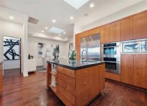 cocina grande con armarios de madera y encimera negra en Elegant Three-Bedroom Beachfront Home With Wide Ocean Views, en Redondo Beach