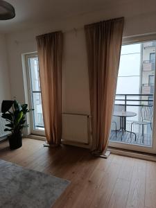 un soggiorno con tende e un tavolo su un balcone di Old Town Bulwar Apartment a Elblag