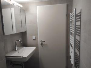 La salle de bains est pourvue d'un lavabo et d'une porte blanche. dans l'établissement FeWo Garmisch, à Garmisch-Partenkirchen