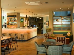 a restaurant with tables and chairs and a bar at B&B HOTEL Ipswich in Ipswich