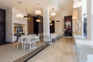Un comedor con mesas blancas y sillas blancas. en B&B Hotel Savona, en Savona