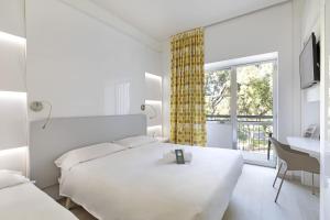 Un dormitorio blanco con una cama, un escritorio y una ventana. en B&B Hotel Savona, en Savona