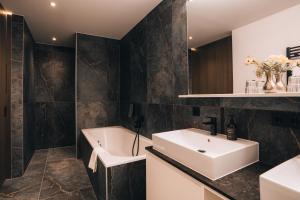a bathroom with a white sink and a bath tub at Hotel Nassereinerhof in Sankt Anton am Arlberg