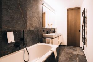 a bathroom with a bath tub and a sink at Hotel Nassereinerhof in Sankt Anton am Arlberg +124 photos