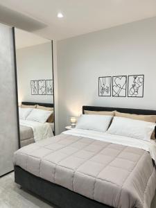 a white bedroom with two beds and mirrors at Mongibello Apartment in Belpasso +17 photos
