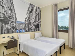 a hotel room with two beds and a desk at B&B Hotel Milano-Monza in Monza