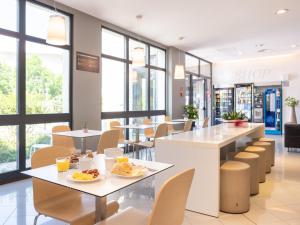 San Giorgio Di MantovaにあるB&B HOTEL Mantovaのテーブルと椅子と窓のあるレストラン