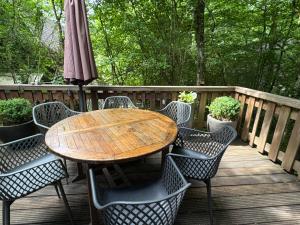 una mesa de madera y sillas en una terraza con sombrilla en Sequoia Duo 2 chalets voisins, familles,amis,détente, en Durbuy