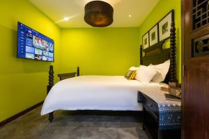 a green bedroom with a bed and a tv at Hotel Cote Cour Beijing in Beijing