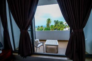 a table and a chair in a room with a window at Harbour View Resort & Apartment in Ambalangoda