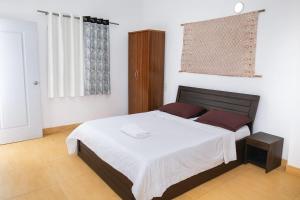 a bedroom with a bed with white sheets and red pillows at ll MOCKTAIL VILLA ll AC ll PRIATE POOL ll in Lonavala