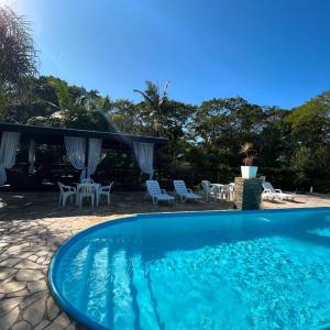 a large swimming pool with chairs and a patio at Recanto Carvalho - Suíte 2 in Itapoa