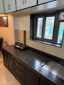 a kitchen with a black counter top and two windows at Golden Maple Villa in Jāmb