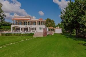 una grande casa con un prato verde davanti di Rivazzurra Beachfront Luxury Villa a Lithakia