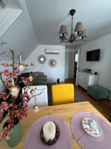 a dining room table with a vase of flowers on it at Pancsoló Rigó & Mérges Harkály Apartments in Dunapataj