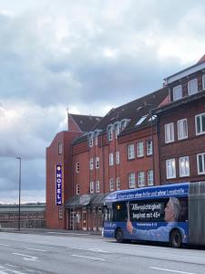 een blauwe bus geparkeerd voor een bakstenen gebouw bij Hotel an der Hörn in Kiel