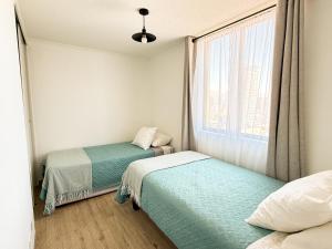 two beds in a small room with a window at Departamento cerca de Cavancha Estacionamiento incluido in Iquique