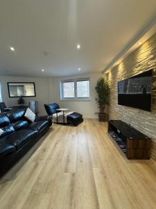 een woonkamer met een zwarte leren bank en een flatscreen-tv bij KM Granton Apartment in Edinburgh
