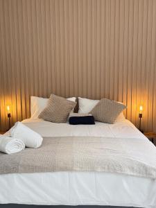 un letto grande con lenzuola e cuscini bianchi di Tambo Touchdown Suites a Benoni