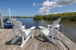 zwei weiße Stühle auf einem Dock in der Nähe des Wassers in der Unterkunft 4B Waterfront Game Room Pool Hot Tub Dock in Palm Harbor