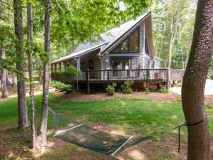 una casa nel bosco con un'amaca davanti di Queen Ridge Cabin a West Jefferson