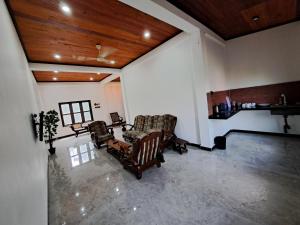 a living room with two chairs and wooden ceilings at Palm Breeze Kokuvil in Jaffna