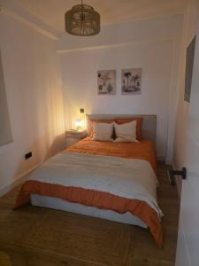 a bedroom with a large bed with orange and white sheets at Sweet Dreams Olivares in Talavera de la Reina