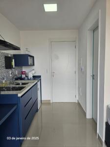 a kitchen with blue cabinets and a white wall at Studio | Expo Stay Tucuruvi Metro |Swimming pool in São Paulo
