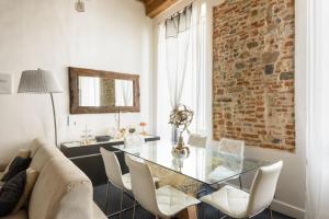 een eetkamer met een glazen tafel en een bakstenen muur bij E quindi uscimmo a riveder le stelle in Florence