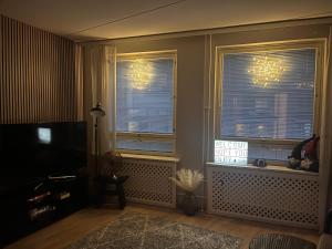 a living room with two windows and a television at Great two bedrooms apartment with a private sauna and a sea view from the balcony close Helsinki center in Helsinki