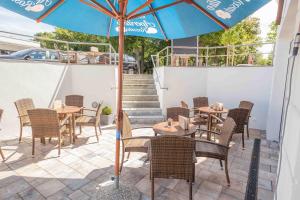 eine Terrasse mit Tischen, Stühlen und einem Sonnenschirm in der Unterkunft Ostseehotel Warnemünde in Warnemünde