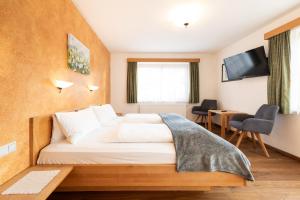 ein Hotelzimmer mit einem Bett und einem Fernseher in der Unterkunft Gästehaus Hartweger in Haus im Ennstal + 60 Fotos