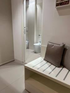 Baño blanco con sofá y aseo en NINFEA sweethome, en Foggia