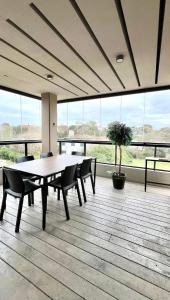 a dining room with a table and chairs and windows at Btwins Pinamar in Pinamar