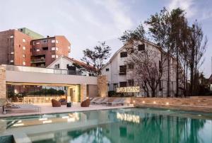 a swimming pool in front of a building at Btwins Pinamar in Pinamar