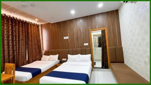 Una habitación de hotel con dos camas y un espejo. en Near Mahakal Temple G- Residency Near Railway Station - Air Conditioned hotel at Prime Location - Lift and Parking - BEST HOTEL IN UJJAIN, en Ujjain