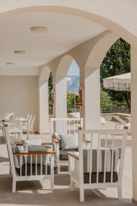 un portico con sedie bianche e un arco di Rivazzurra Beachfront Luxury Villa a Lithakia