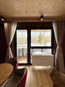 a living room with a large window and a table and chairs at Apartmán Forest, Tatranská Štrba in Tatranska Strba