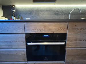 a black oven in a kitchen with wooden cabinets at Casa dei cugini in Oga +40 photos