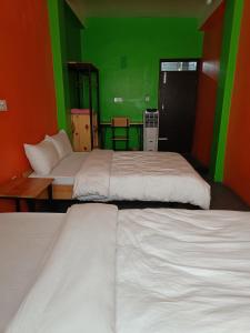 two beds in a room with green and orange walls at Hotel Baishnav in Upardāng Garhi