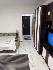 Zimmer mit einem Bett, einem TV und einer Tür in der Unterkunft Garsonieră parter, 1 dormitor cu terasa si loc de joacă, PARCARE GRATUITĂ, Craiova in Craiova
