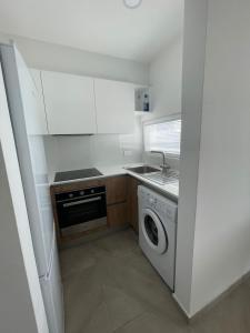 una pequeña cocina con lavadora y fregadero en Elite 1BD Flat with Pool in Harbor area, en Lárnaca 3 fotos más