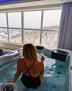 a woman sitting in a bath tub with a glass of wine at Wellness pod zvezdami, Maribor - PRIVATE in Maribor