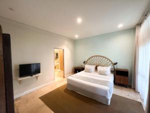 a bedroom with a bed and a flat screen tv at Kresna By The Sea By Kresna Hospitality in Seminyak