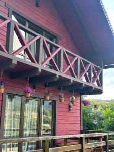 a red house with potted plants on the porch at Фазенда in Vorokhta