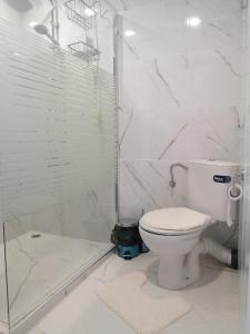 a white bathroom with a toilet and a shower at Уют in Haskovo