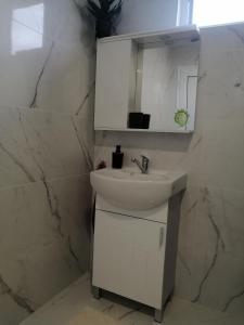 a white bathroom with a sink and a mirror at Уют in Haskovo