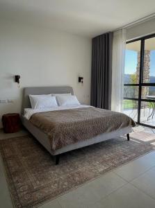 a bedroom with a large bed and a large window at Calma Hermon Guest Rooms in Neve Ativ